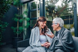 a woman sits with her senior loved one at a visit to the assisted living facility