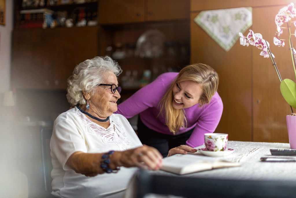an assisted living employee leans down to a senior woman to explain the differences between hospice vs respite care