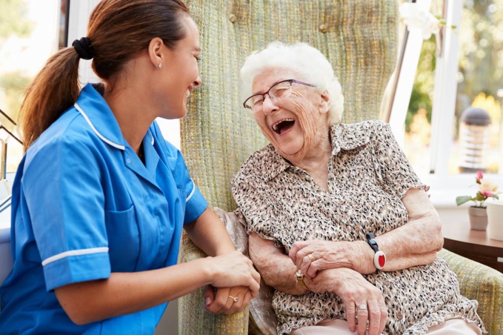 Skilled nurse laughing with a senior adult outside