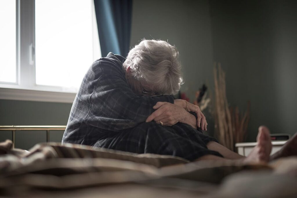 Woman holds herself in bed as she wonders about Alzheimer's causes
