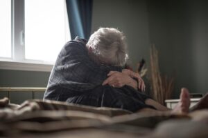 Woman holds herself in bed as she wonders about Alzheimer's causes
