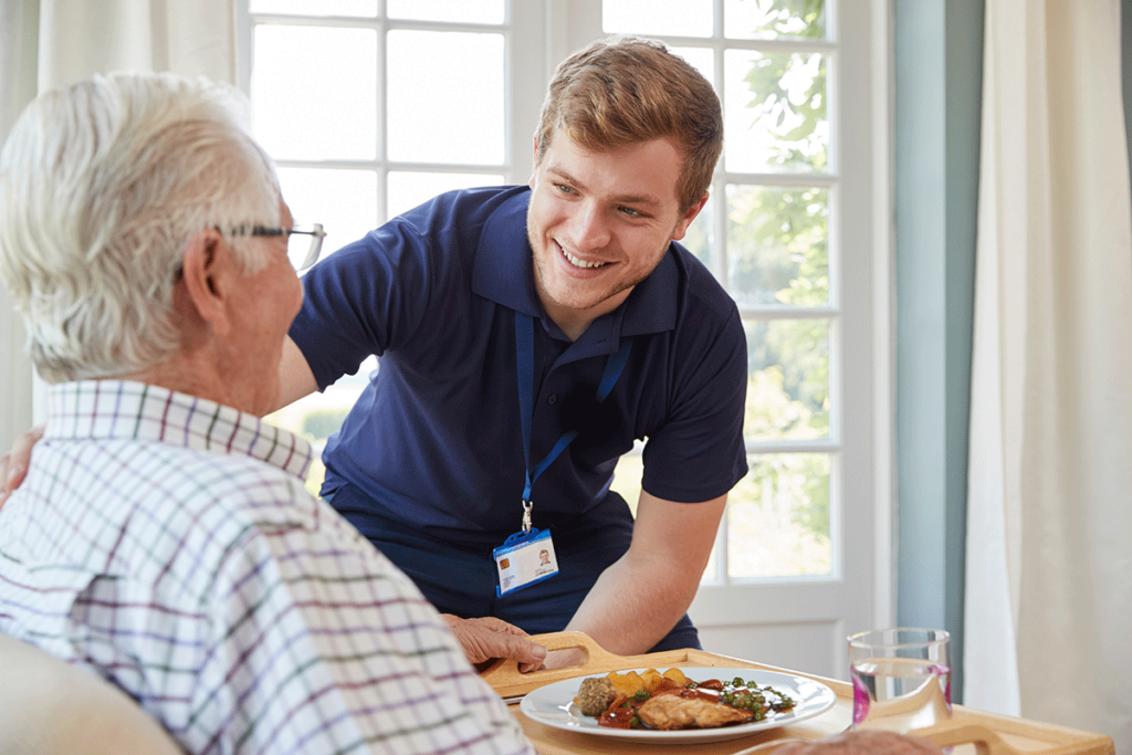 Nurse smiles as he chats with senior in respite care in Houston, TX
