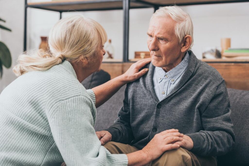 Person puts arms on another while assisting a person with dementia