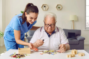 Nurse talks to senior about communication techniques with memory-impaired seniors while he completes a puzzle