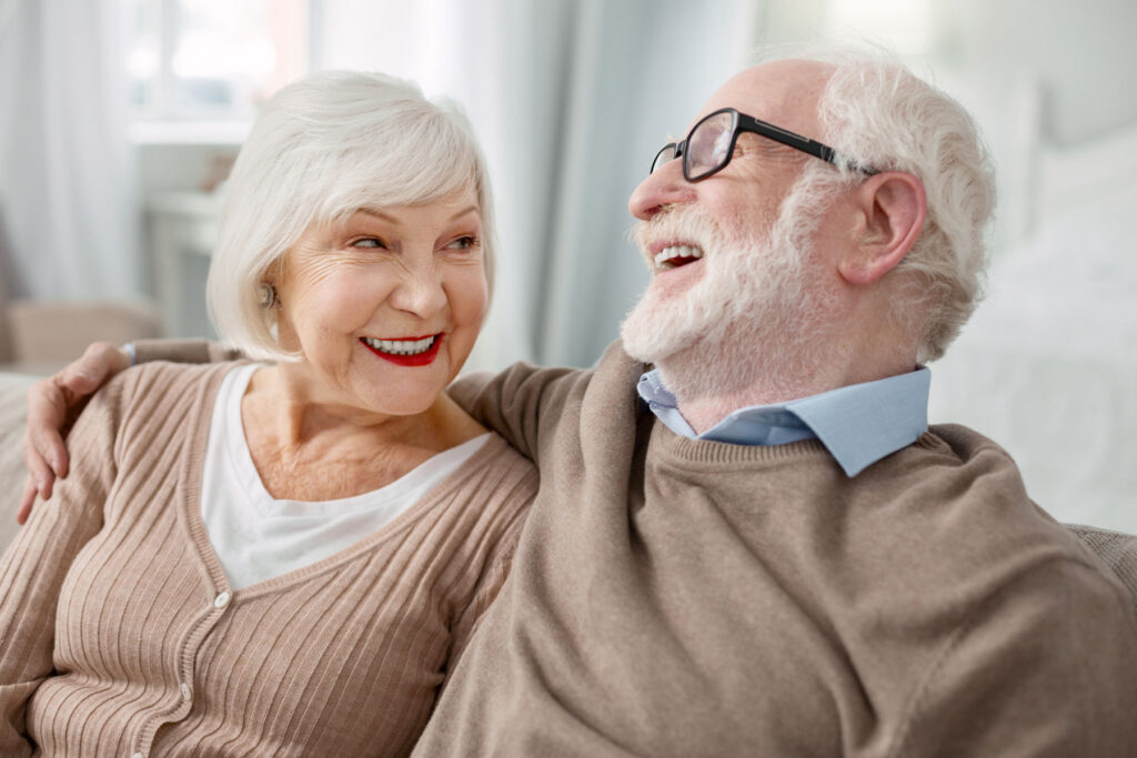 Senior couple cuddles on couch as they discuss essential skills for senior independent living