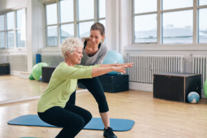 Woman squats with therapist during senior physical therapy techniques