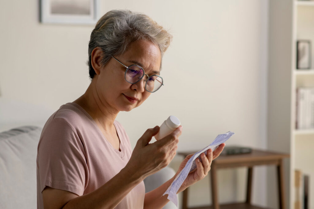 Woman looks at pill bottle while organizing her medications