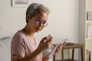 Woman looks at pill bottle while organizing her medications