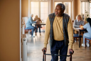 Senior walks down hall while smiling thinking about physical therapy exercises for enhancing senior mobility
